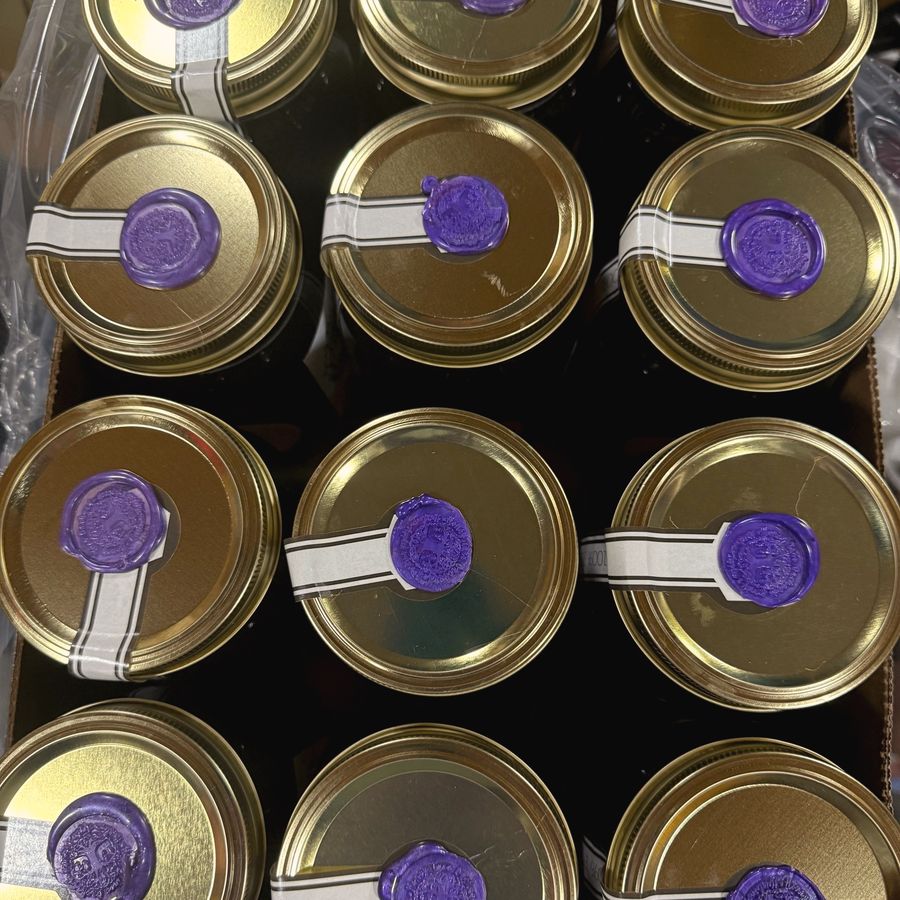 Jars of honey with gold lids and wax seals, seen from above, Honey Tree Orchard & Apiary